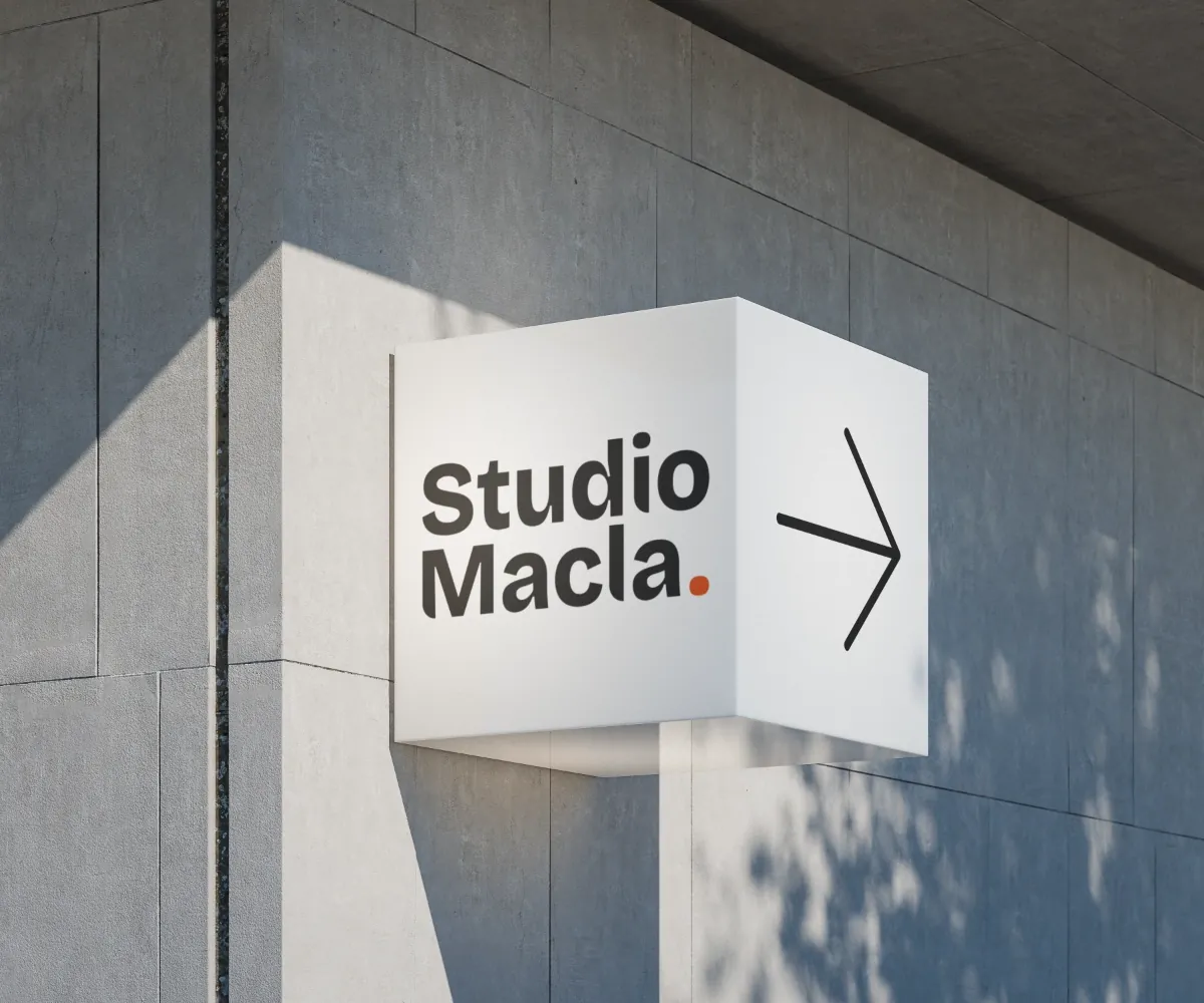 Logo Studio Macla sur une enseigne en caisson, au-dessus de l’entrée d’un bâtiment en béton