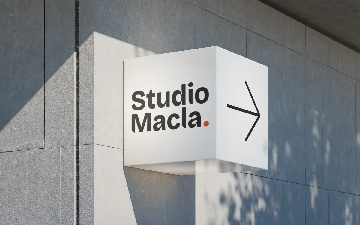 Enseigne en caisson lumineux portant le logo Studio Macla, sur une façade en béton